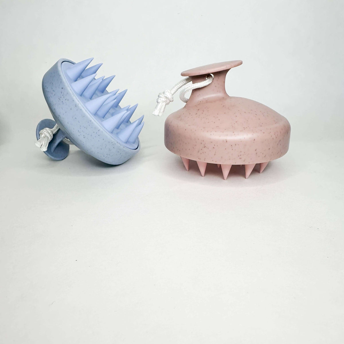 Blue and pink scalp massagers on a white background
