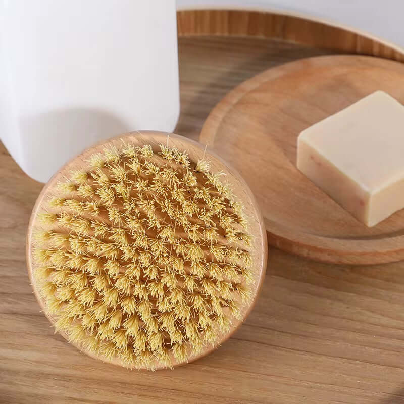 Natural bristle brush on a wooden surface with a bar of soap and a white container in the background.