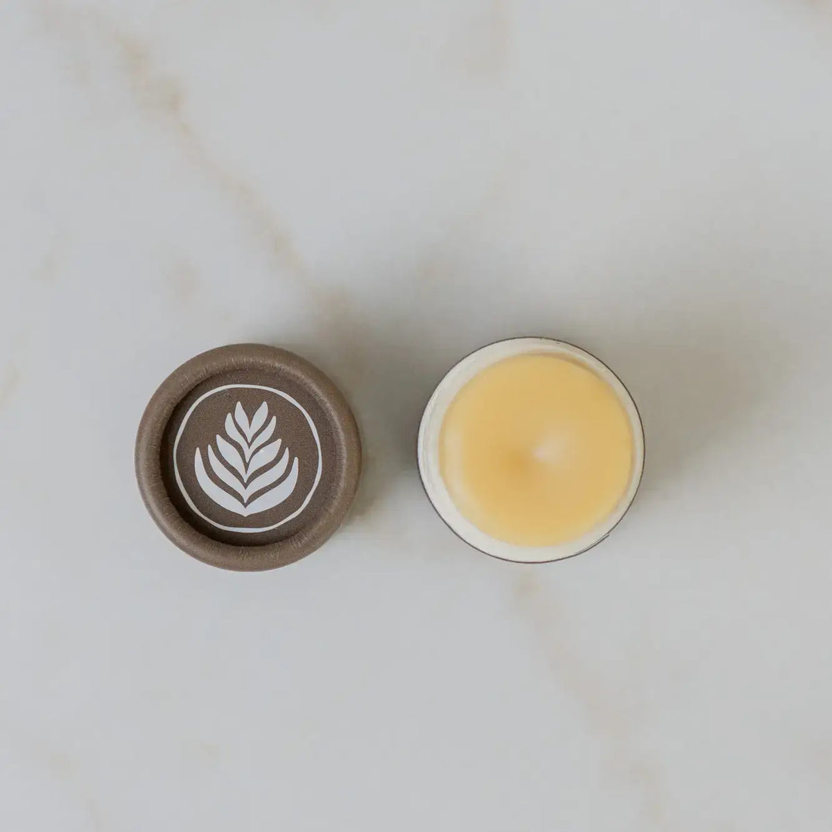 Small container with a lid featuring a leaf design on a light background