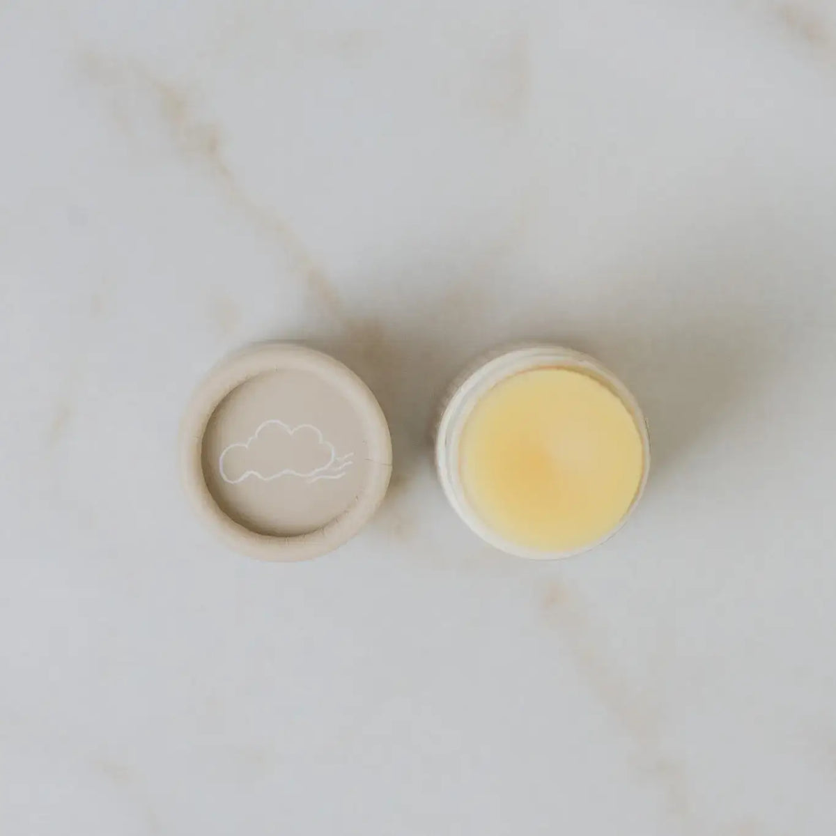 Two small containers with a cloud design on a marble surface