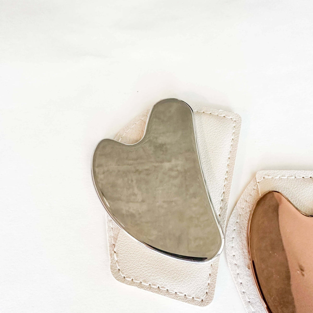 Metal gua sha tool on a white background