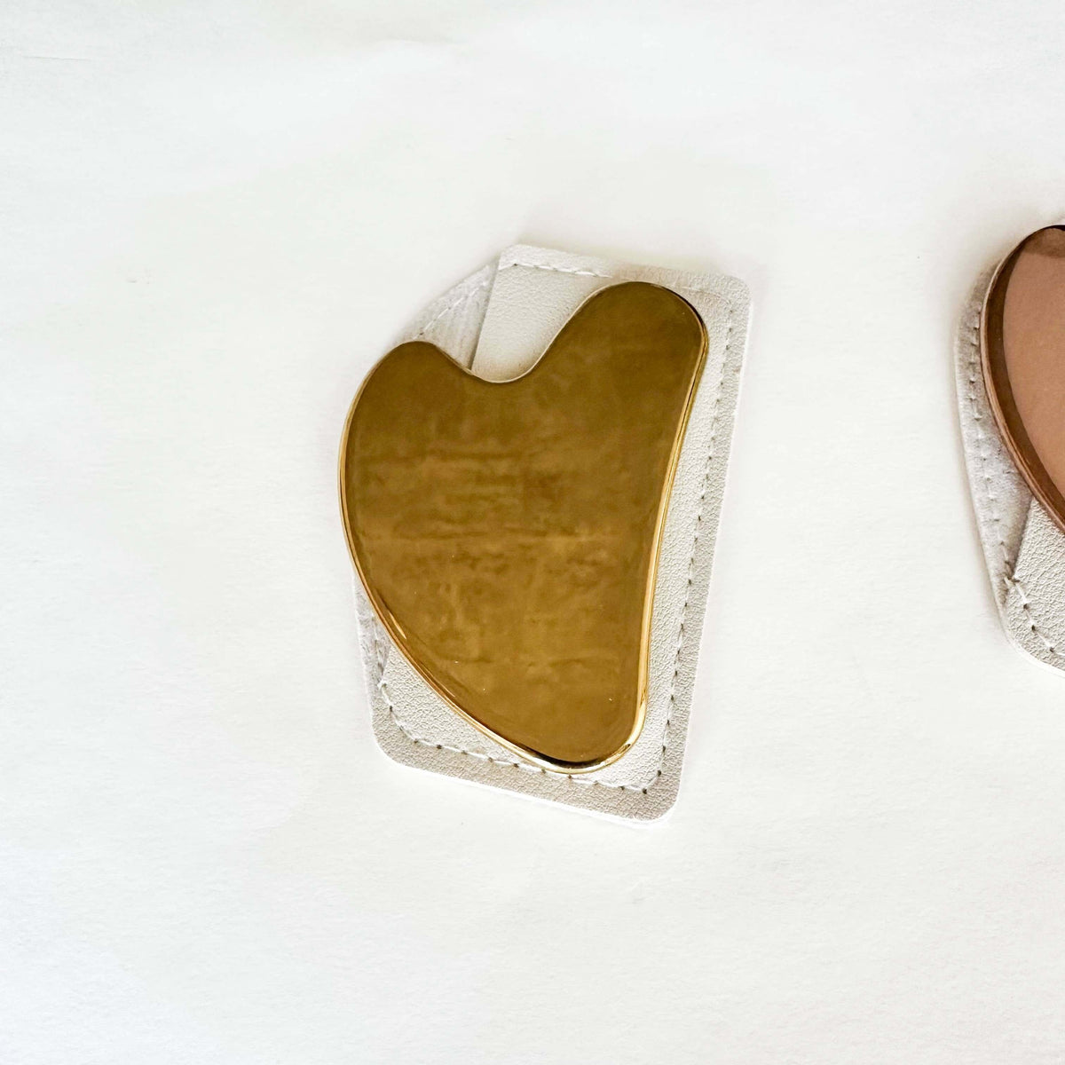 Gold gua sha tool on a white background