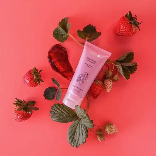Strawberry Brightening Scrub with fresh strawberries on a vibrant pink background, showcasing fruity rejuvenation.