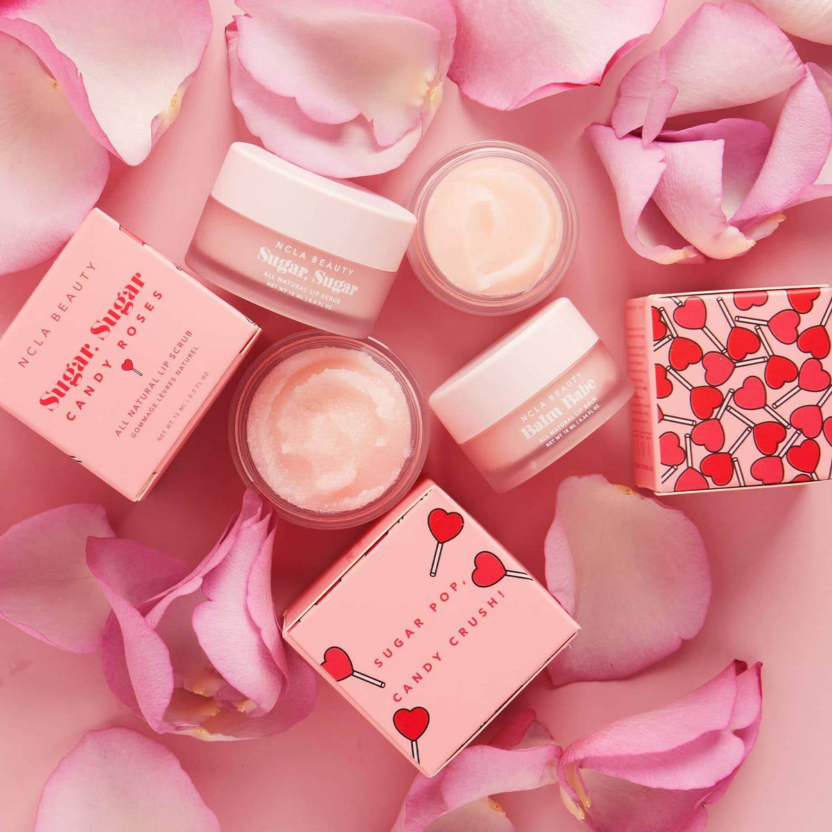 Cosmetic products with pink packaging and rose petals on a pink background
