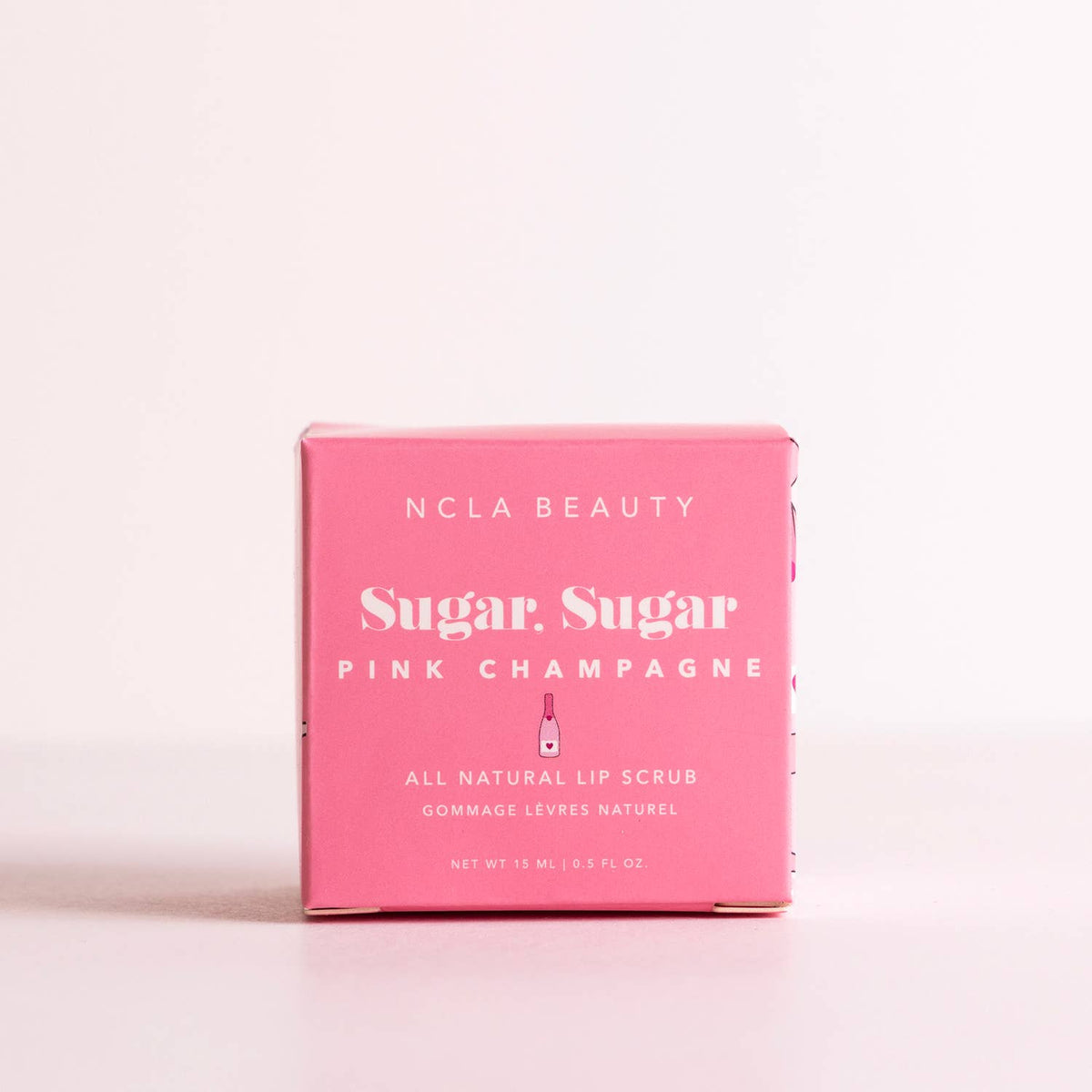 Pink box of NCLA Beauty Sugar Sugar Pink Champagne lip scrub on a light pink background