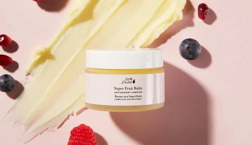 Super Fruit Balm jar surrounded by berries and balm on a pink background, deeply nourishes dry or sensitive skin.