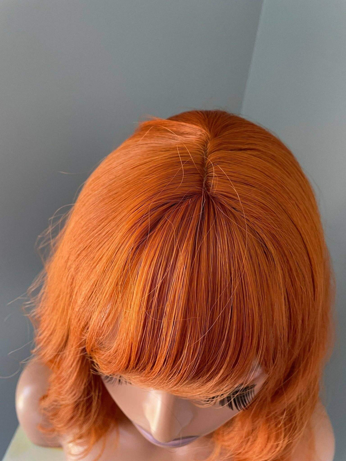 Orange Wig with Bangs showcasing vibrant tangerine color and stylish short cut.