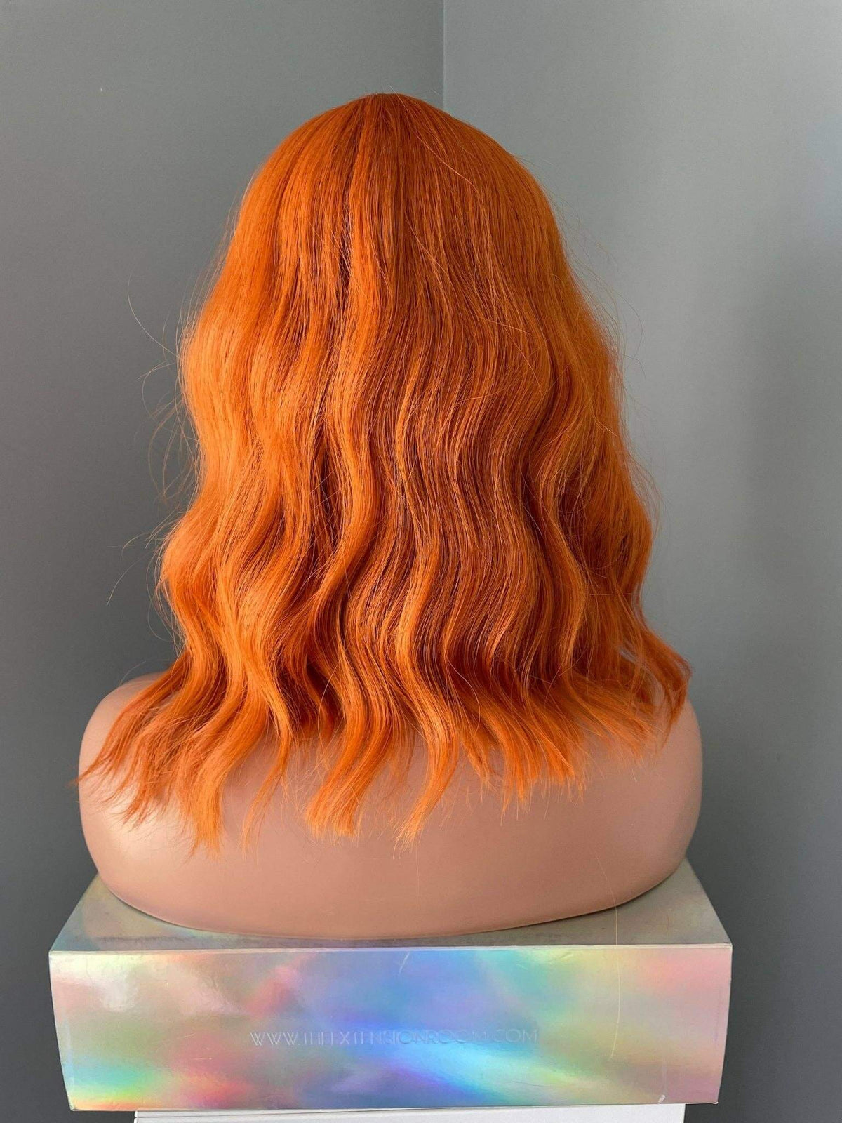 Back view of a Tangerine Short Orange Wig with Bangs showcasing vibrant orange waves.