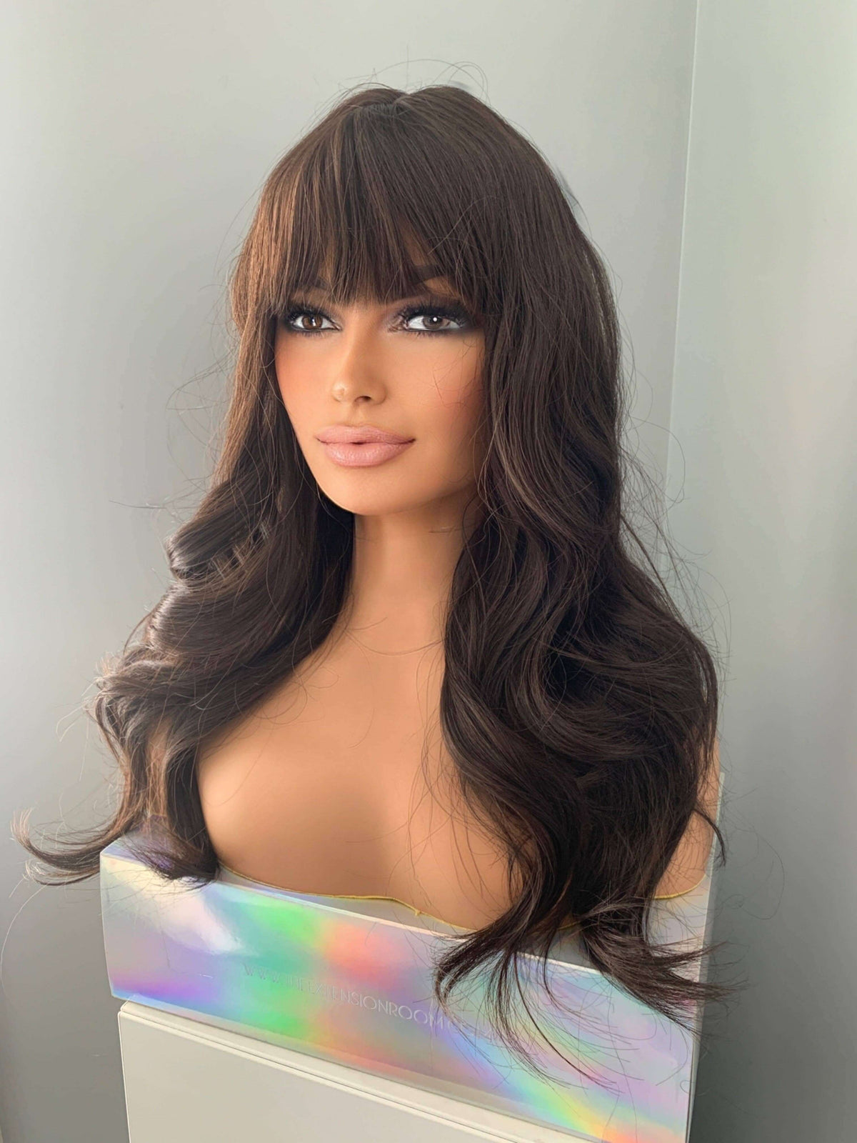 Tasha Long Dark Chocolate Brown Wig with Bangs displayed on a mannequin, featuring soft waves and full fringe.