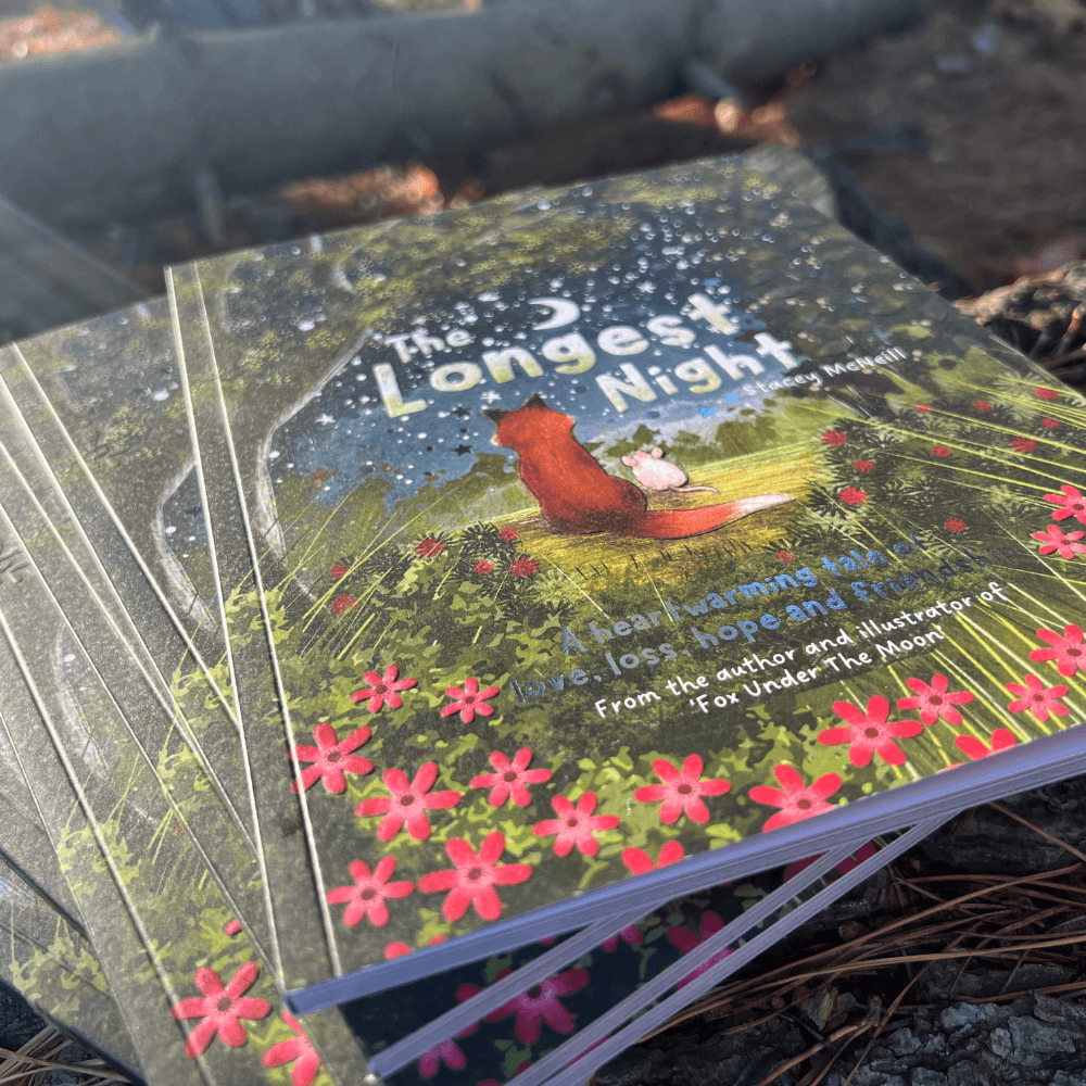 The Longest Night Paperback Book + bookmark displayed on a bed of leaves, emphasizing themes of grief and hope.
