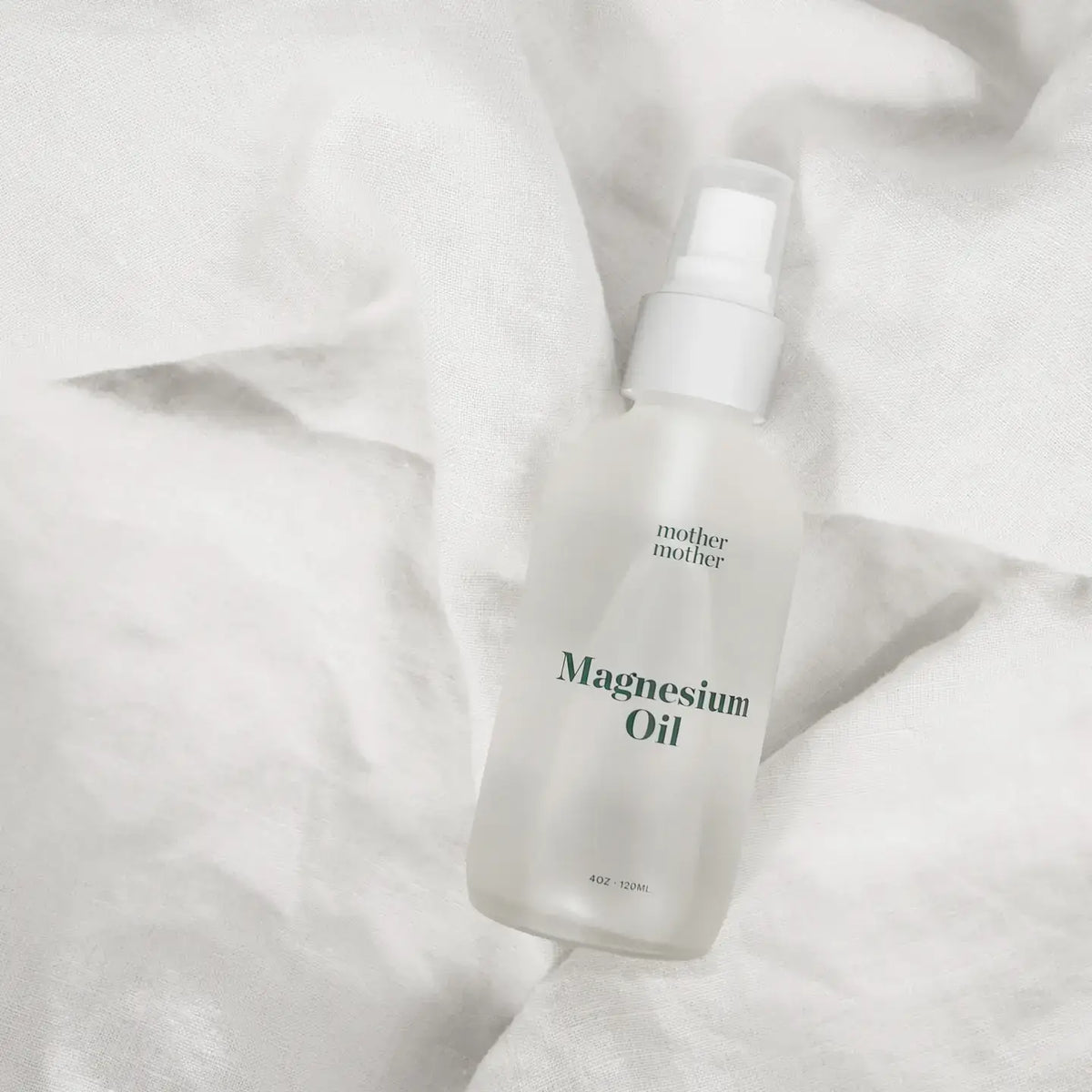 Bottle of magnesium oil with 'mother' branding on a white fabric background
