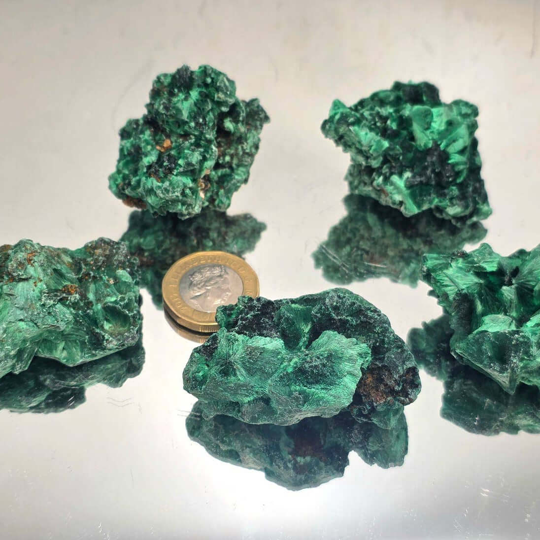Velvet Malachite Crystals Natural 200g showcased with a coin, displaying the vibrant emerald-green colors and unique textures.