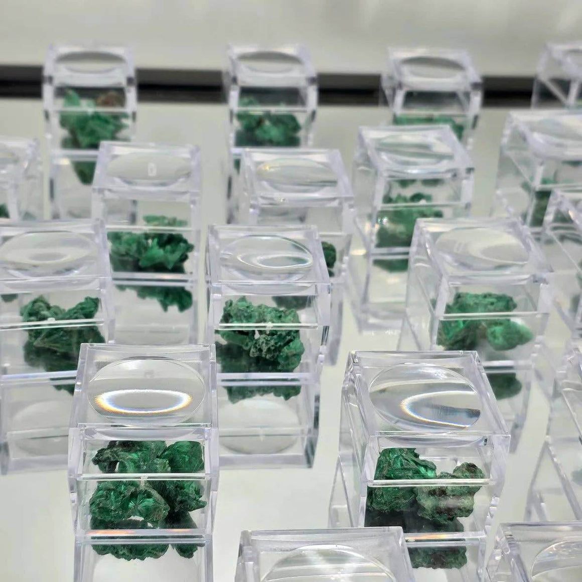 Velvet Malachite Raw In Magnifying Box showcasing emerald-green specimens in display boxes.