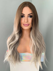 Long wavy grey silver wig featuring natural beachy waves and blended ash brown and blonde highlights.