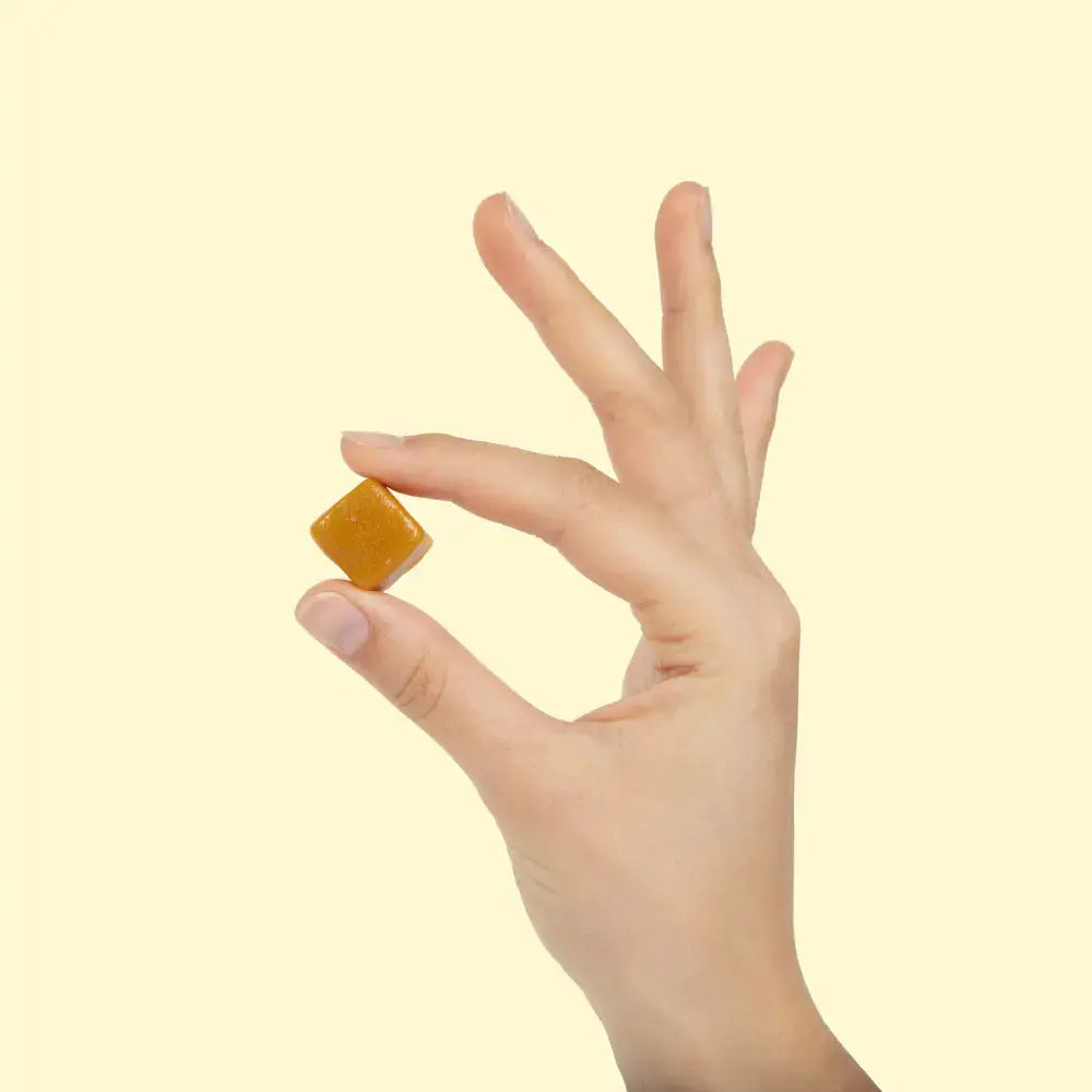 Hand holding a WonderBee® Chews superfood honey gummy for immune health and wellbeing.
