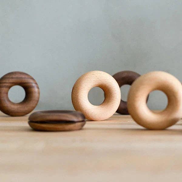 Wooden donut-shaped objects on a wooden surface with a neutral background