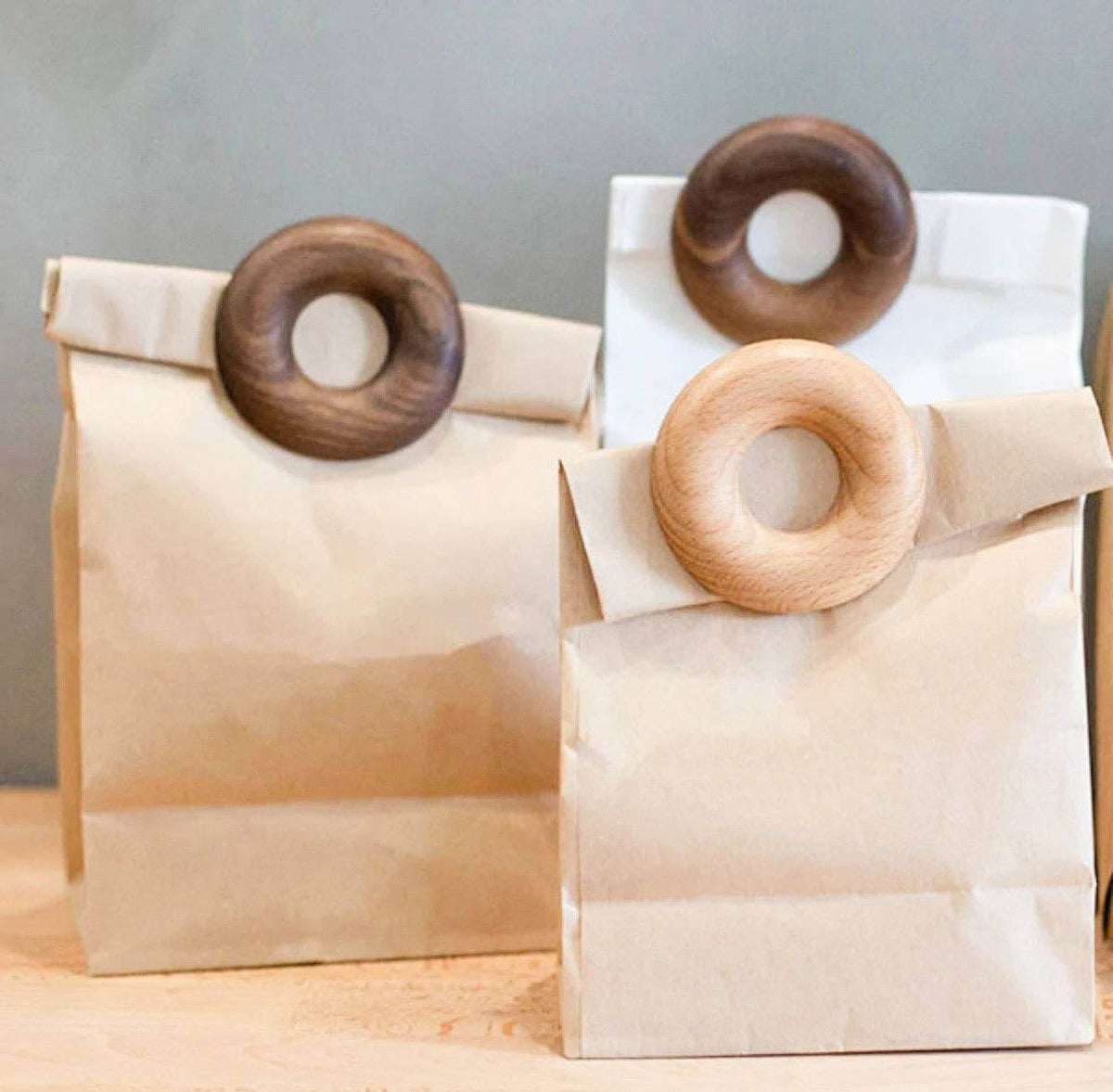 Three paper bags with wooden rings on a wooden surface and gray background