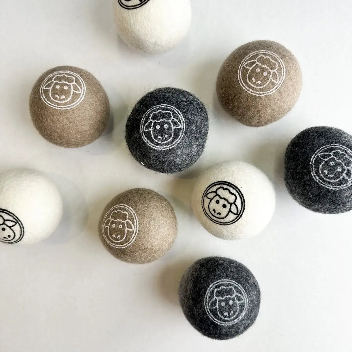 Set of round felt balls with sheep emblem on a white background