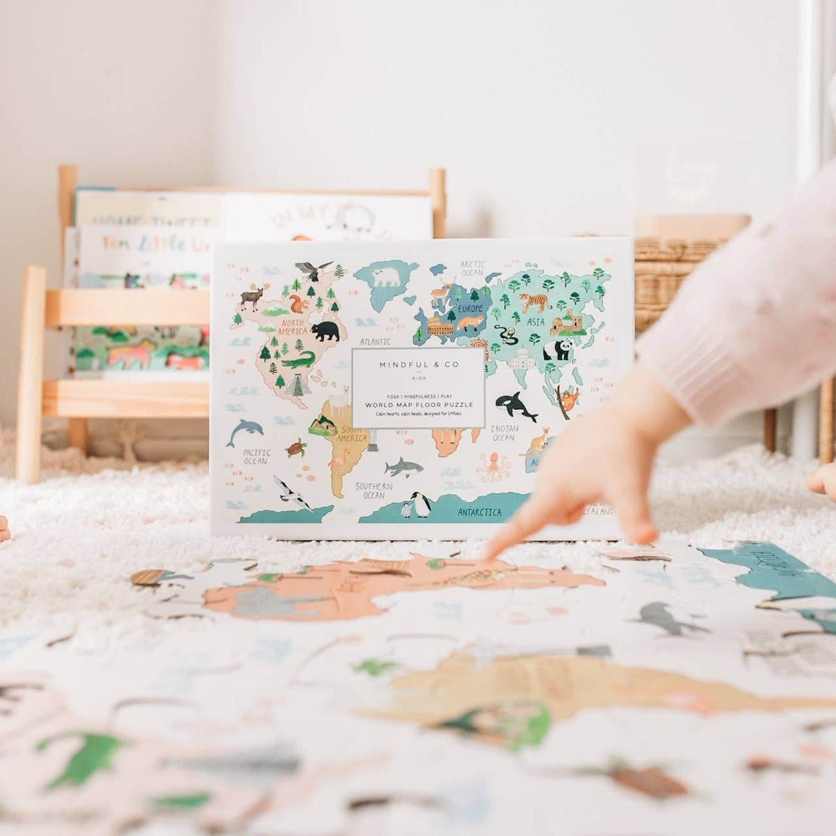 Child engaging with the World Map Floor Puzzle on a carpet, featuring colorful continents and animals.