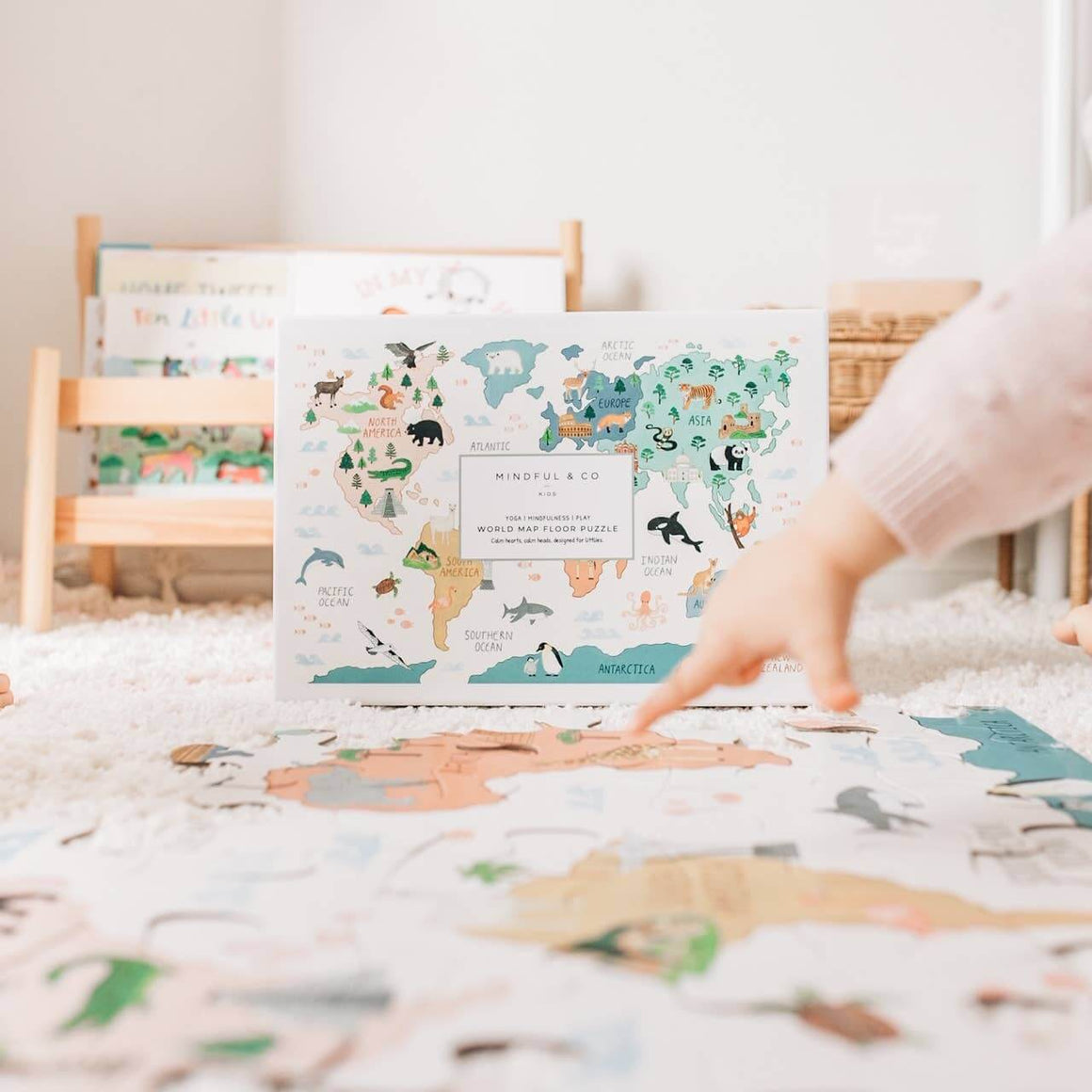 Child engaging with the World Map Floor Puzzle on a carpet, featuring colorful continents and animals.