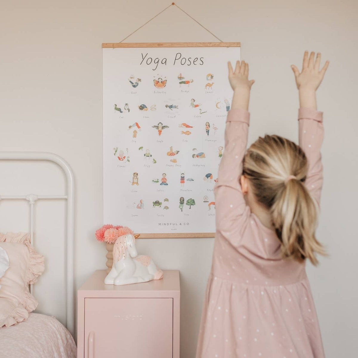 Child practicing yoga poses in front of Yoga Poses Print educational poster for mindfulness and focus.