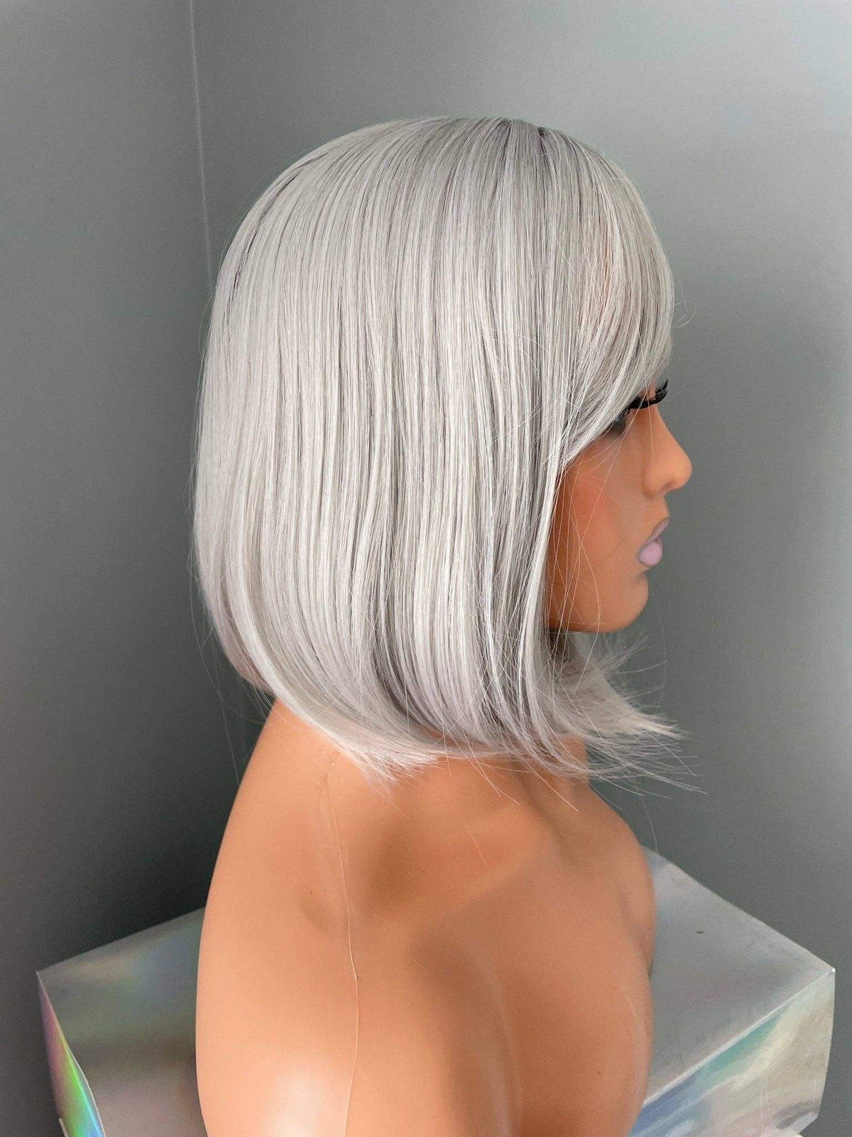 Side view of a mannequin displaying the Yvette short silver bob wig in a stylish ash silver color.