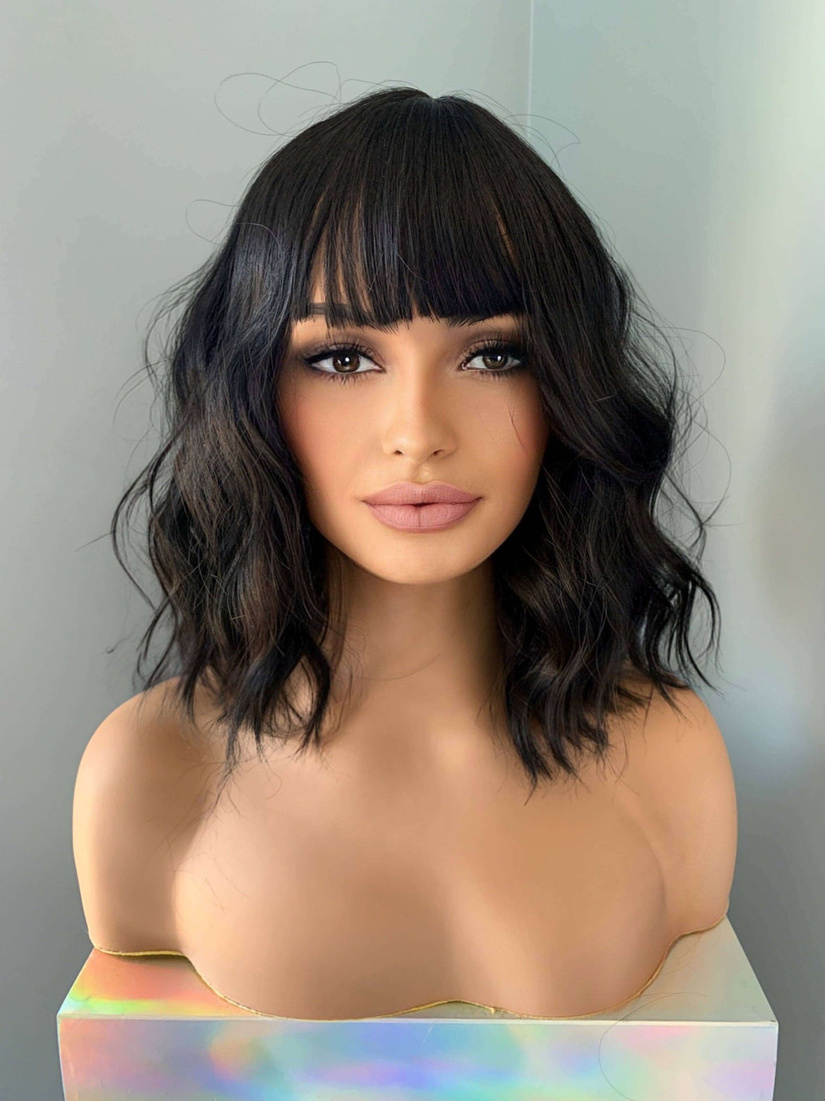 Woman with styled black hair against a neutral background