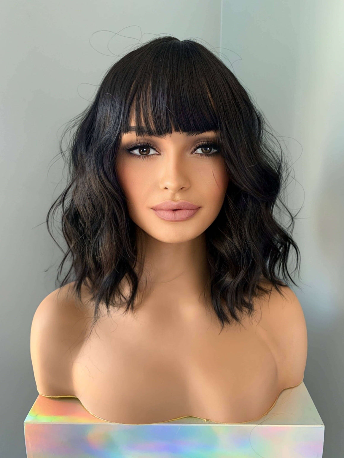 Woman with styled black hair against a neutral background