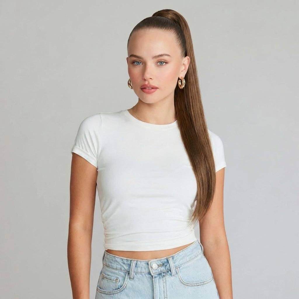 Model showcasing auburn brown ponytail hair extension with silky straight texture in a white top.