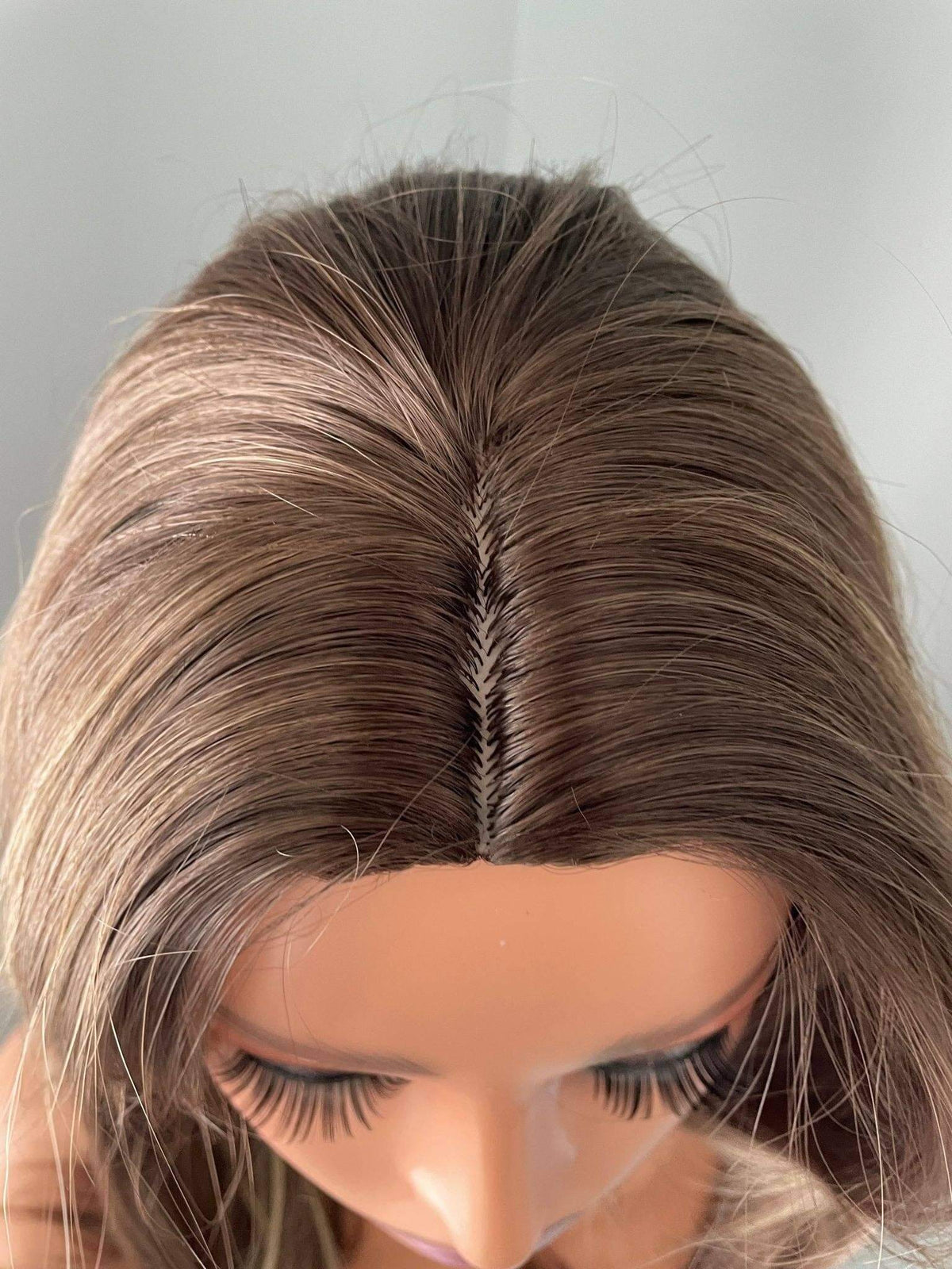 Close-up of a person with brown hair styled in a way that highlights the hairline.