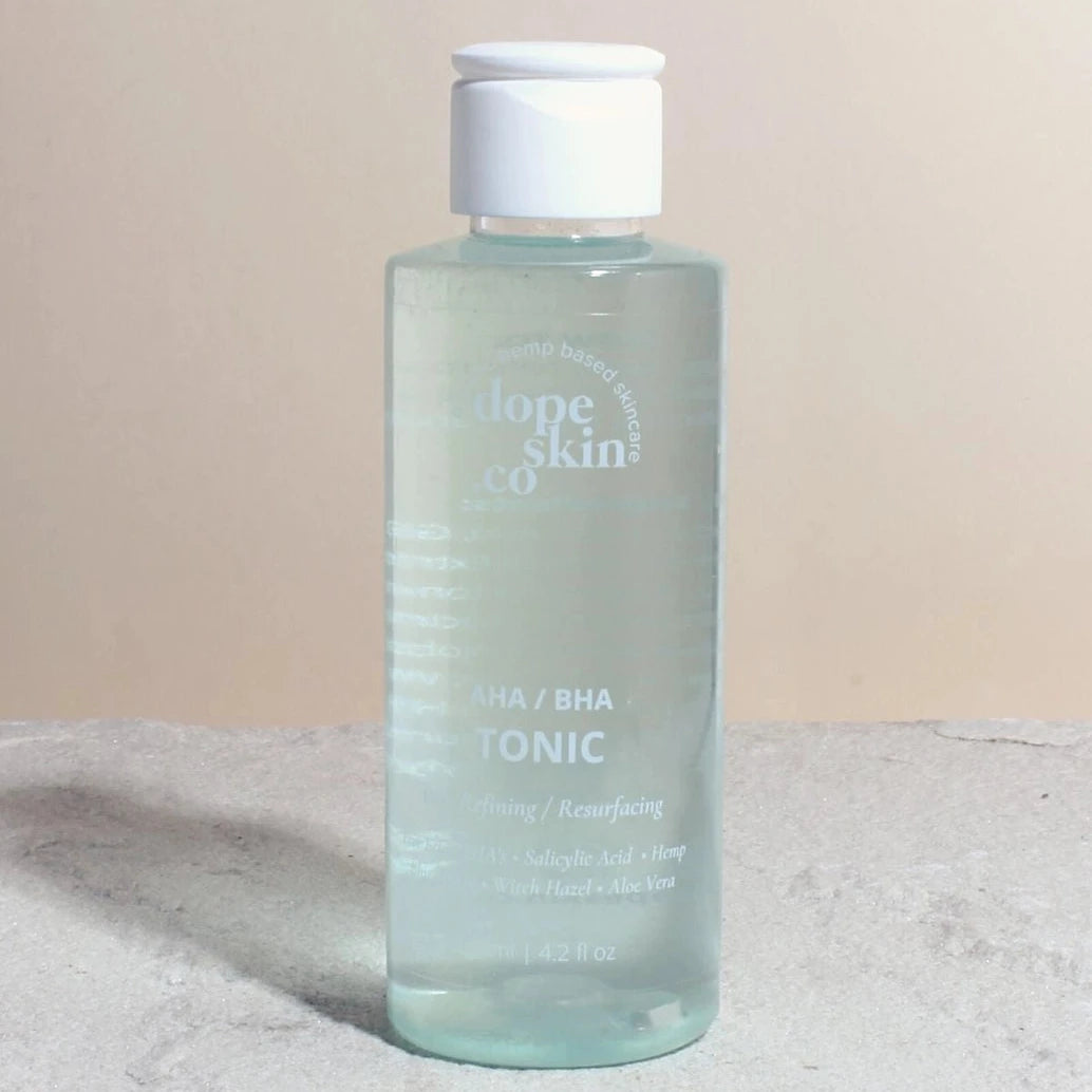 Clear bottle of 'unique skin co.' tonic on a light background