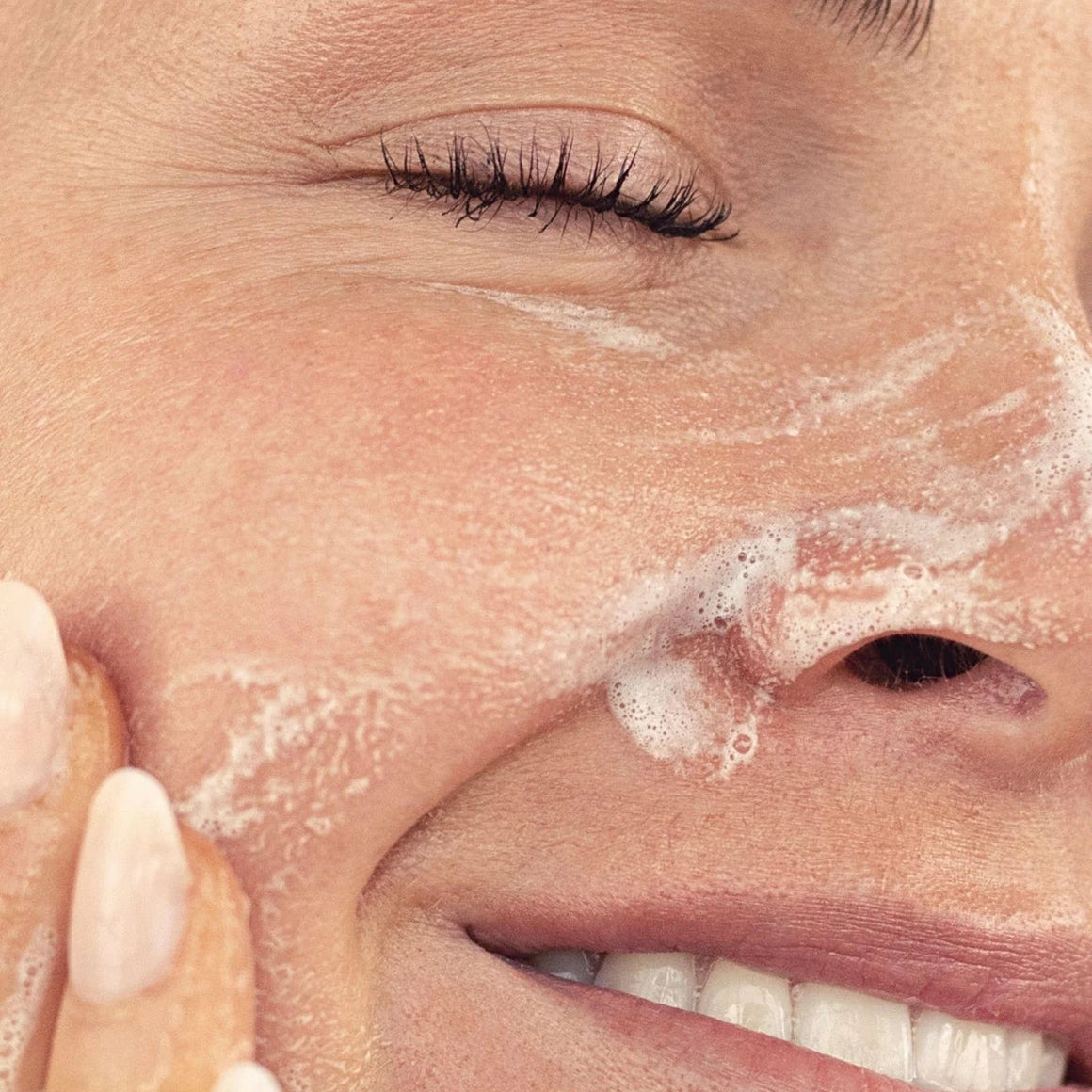 Close-up of a person applying facial cleanser to their face